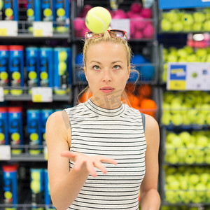 购物娱乐摄影照片_女人在运动服店购物网球。