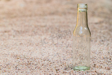 海洋塑料垃圾污染摄影照片_沙子上的空玻璃瓶 垃圾污染的概念