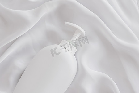 空白标签化妆品容器瓶作为白色丝绸背景上的产品模型