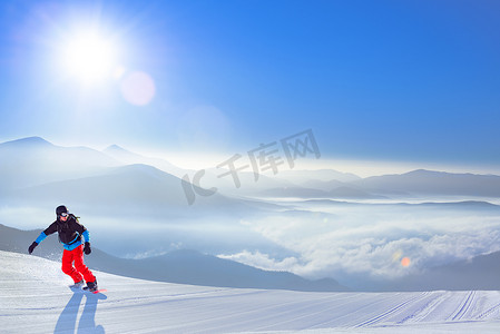 滑雪者在灿烂的阳光下在山坡上骑着红色滑雪板。
