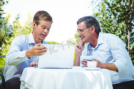 两位商人在一家餐厅使用笔记本电脑开会
