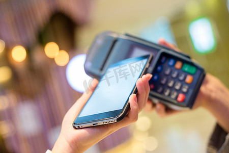 商业手机摄影照片_妇女通过 NFC 技术用手机付款