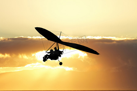 悬挂滑翔机摄影照片_日落时在空中滑翔
