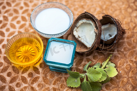 棕色木质表面上头发护理或头发处理成分的特写，即椰奶与生蜂蜜在玻璃碗中充分混合。