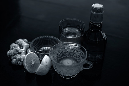 在木质表面的透明杯子中关闭由威士忌、生姜、蜂蜜、水、柠檬和薄荷组成的草药绿茶。