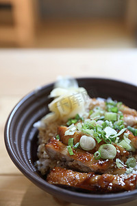 老人烧饭卡通摄影照片_日本食品，木制背景的鸡肉照烧饭