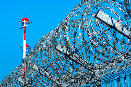 军事机场摄影照片_带铁丝网的围栏和一排机场灯柱与 al