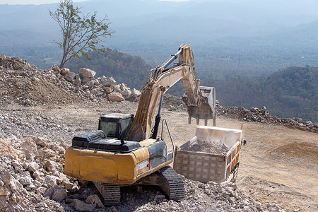 黄色反摄影照片_黄色挖掘机正在煤矿用岩石装满自卸车