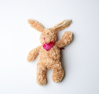 白色兔子摄影照片_玩具棕色毛绒兔子躺在白色背景上