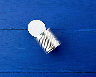 罐装样机摄影照片_从平行的蓝色木质背景上打开大金属锡罐
