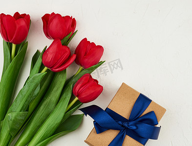 包裹的绿叶摄影照片_一束红色盛开的郁金香与绿叶，包裹的礼物我