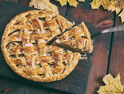 秋天木板背景摄影照片_棕色木板上的圆形苹果派，松饼