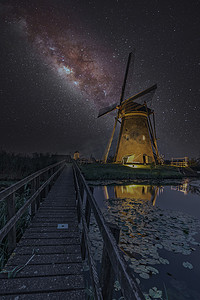在荷兰小孩堤防温暖无云和温暖的天气下，风车上的银河正在履行职责