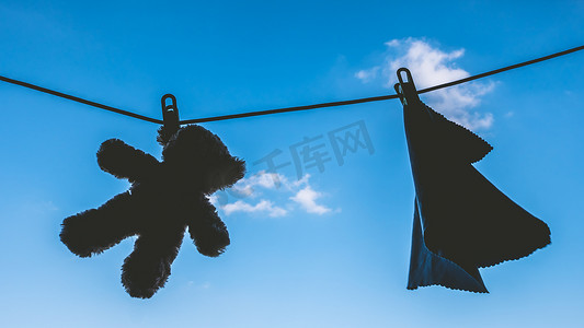 挂在蓝天晾衣绳上的泰迪熊和餐巾的轮廓