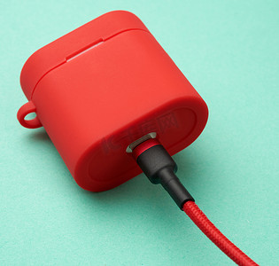 耳机充电摄影照片_带有红色外壳的耳机充电器的盒子连接到电缆