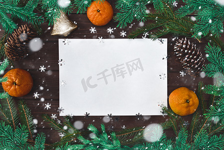 问候语、冷杉树枝、纸、雪花、锥体、铃铛、柑橘类水果和装饰的圣诞背景。