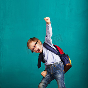 开心跳跃的小男孩摄影照片_背着大背包微笑的小男孩跳跃和玩乐