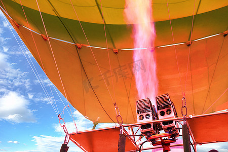 珊瑚色的火从强大的气炬中发出，并用热空气填充气球气球。