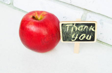 木板黑色背景上带有谢谢题词的苹果