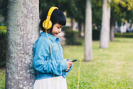 儿童概念和技术 — 戴着耳机听音乐的微笑女孩