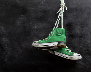 一双破旧的绿色纺织运动鞋挂着
