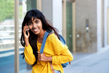微笑的年轻印度女人走路和用手机说话