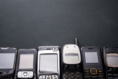 过时的摄影照片_黑色背景上的旧手机和过时的手机。