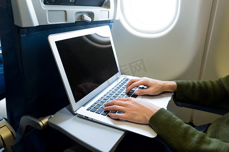 在飞机上使用笔记本电脑的妇女