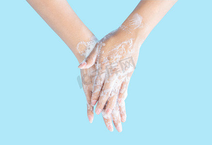上洗手摄影照片_特写女人的手在蓝色背景上用肥皂洗手，健康