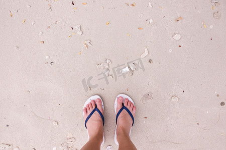 沙滩背景上穿着时尚凉鞋的脚自拍，顶部