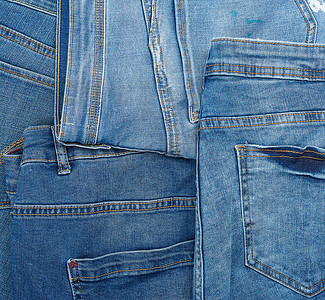 许多蓝色经典牛仔裤杂乱地堆放着，后口袋