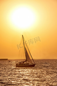 海上帆船运动摄影照片_反对海上日落的帆船