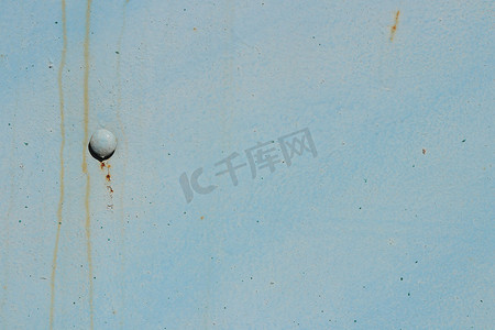 蓝色彩绘墙体纹理上的风化生锈铆钉