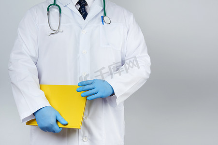黄色手套医用摄影照片_男医生穿着白色医用外套和蓝色乳胶手套