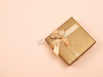 米色背景上带蝴蝶结的封闭式金色礼盒