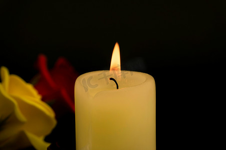 燃烧的黄色蜡烛和两朵玫瑰