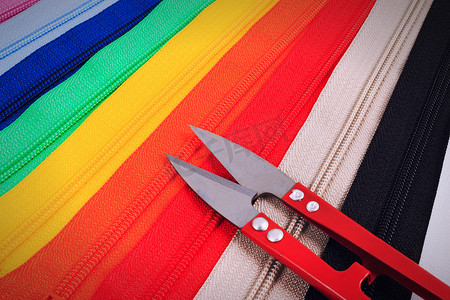 六种不同颜色的彩色拉链上的红色剪刀。
