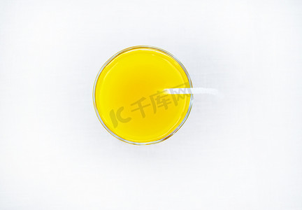 极简主义背景摄影照片_夏日饮品 — 鲜榨橙汁装在带吸管的玻璃杯中，顶视图，白色背景中突显，极简主义风格
