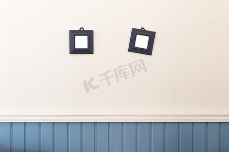 蓝色方框摄影照片_白色和蓝色的墙上挂着两个小方框。