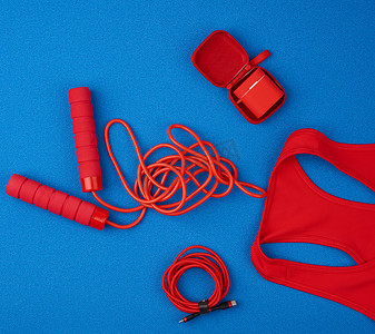 耳机充电摄影照片_红色运动衫、红色跳绳和红色无线耳机