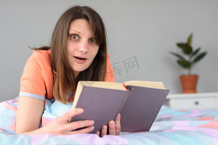 读书成长手册摄影照片_因读书而受到轻微震惊的女孩