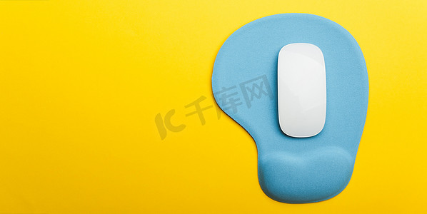 电脑鼠标鼠标垫摄影照片_带无线白色电脑鼠标的蓝色垫或鼠标垫