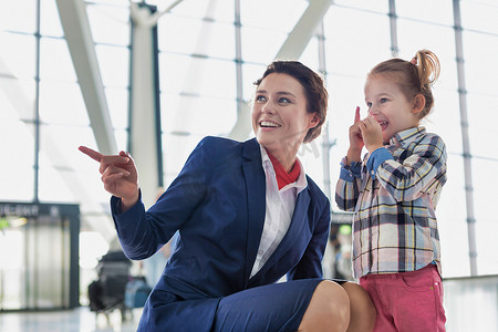 机场工作摄影照片_机场工作人员在机场和可爱的小女孩玩耍的肖像