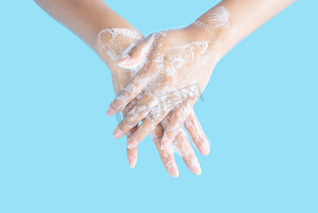 特写女人的手在蓝色背景上用肥皂洗手，健康