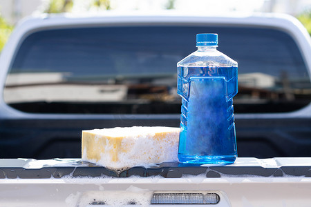 塑料桶摄影照片_关闭瓶与洗涤的黄色海绵的洗车肥皂，