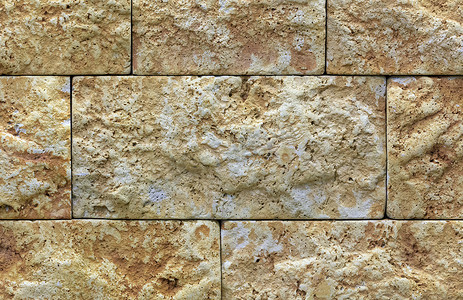 建筑石材摄影照片_石灰石墙的质地，米色金色石灰石的建筑石材。
