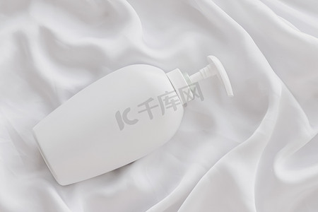 产品模型摄影照片_空白标签化妆品容器瓶作为白色丝绸背景上的产品模型