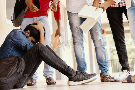 青少年学生摄影照片_十几岁的男孩在学校被欺负，捂着脸 — 一群学生威胁要打大学同学或大三学生 — 大学校园里戏弄、欺凌或警告的概念。