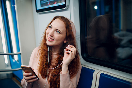 年轻女子在地铁里用手机听音乐。