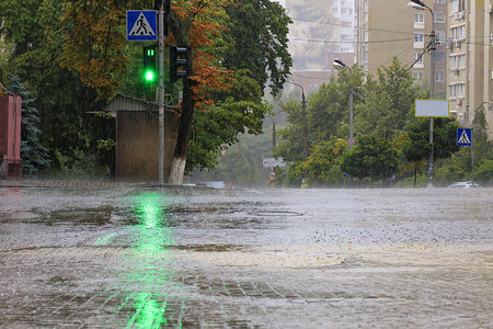 照亮黑暗摄影照片_绿色交通灯照亮了人行道和柏油路上的大雨。